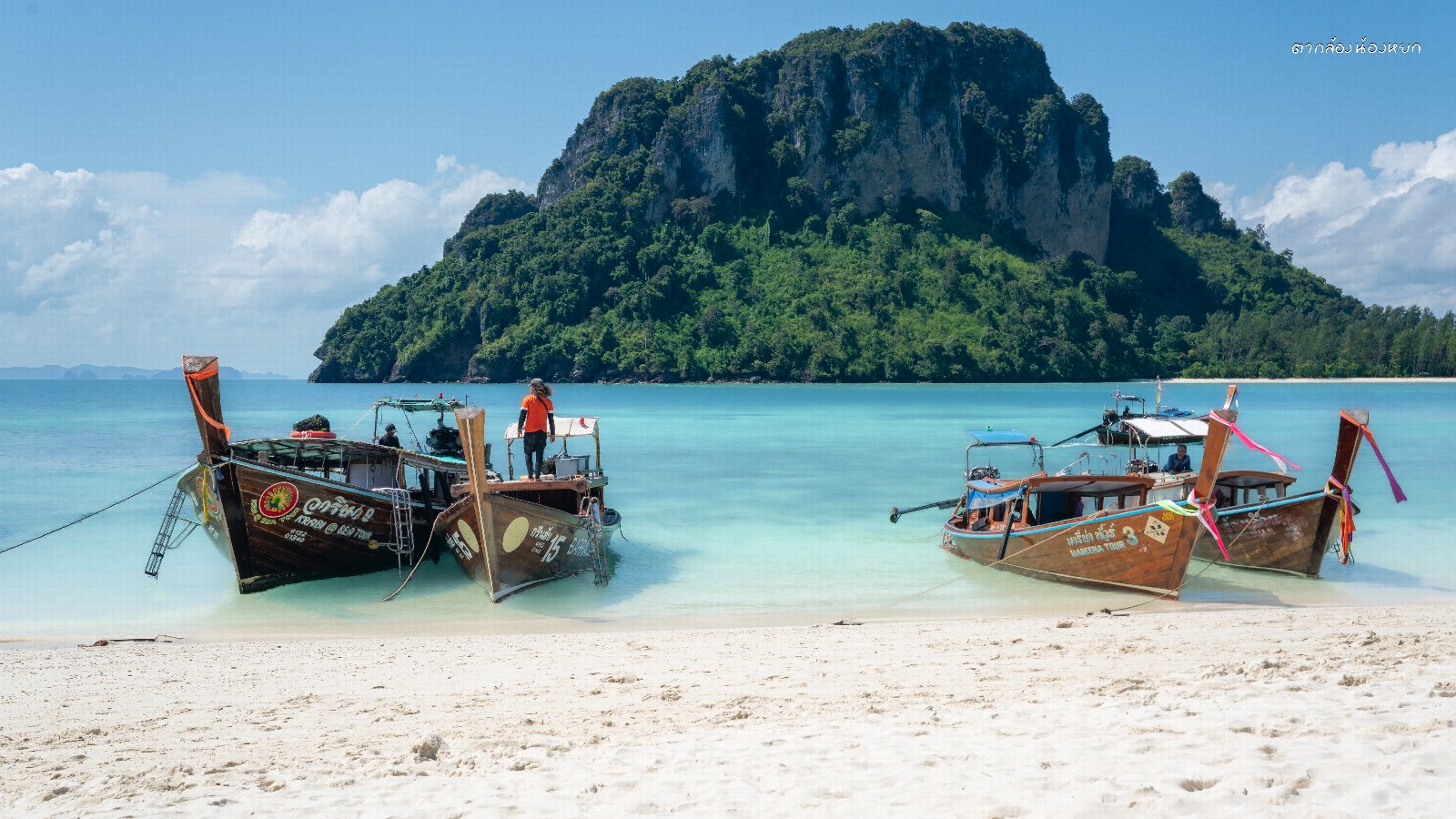 เรือดั้งเดิมจอดอยู่ริมทรายกับน้ำใส