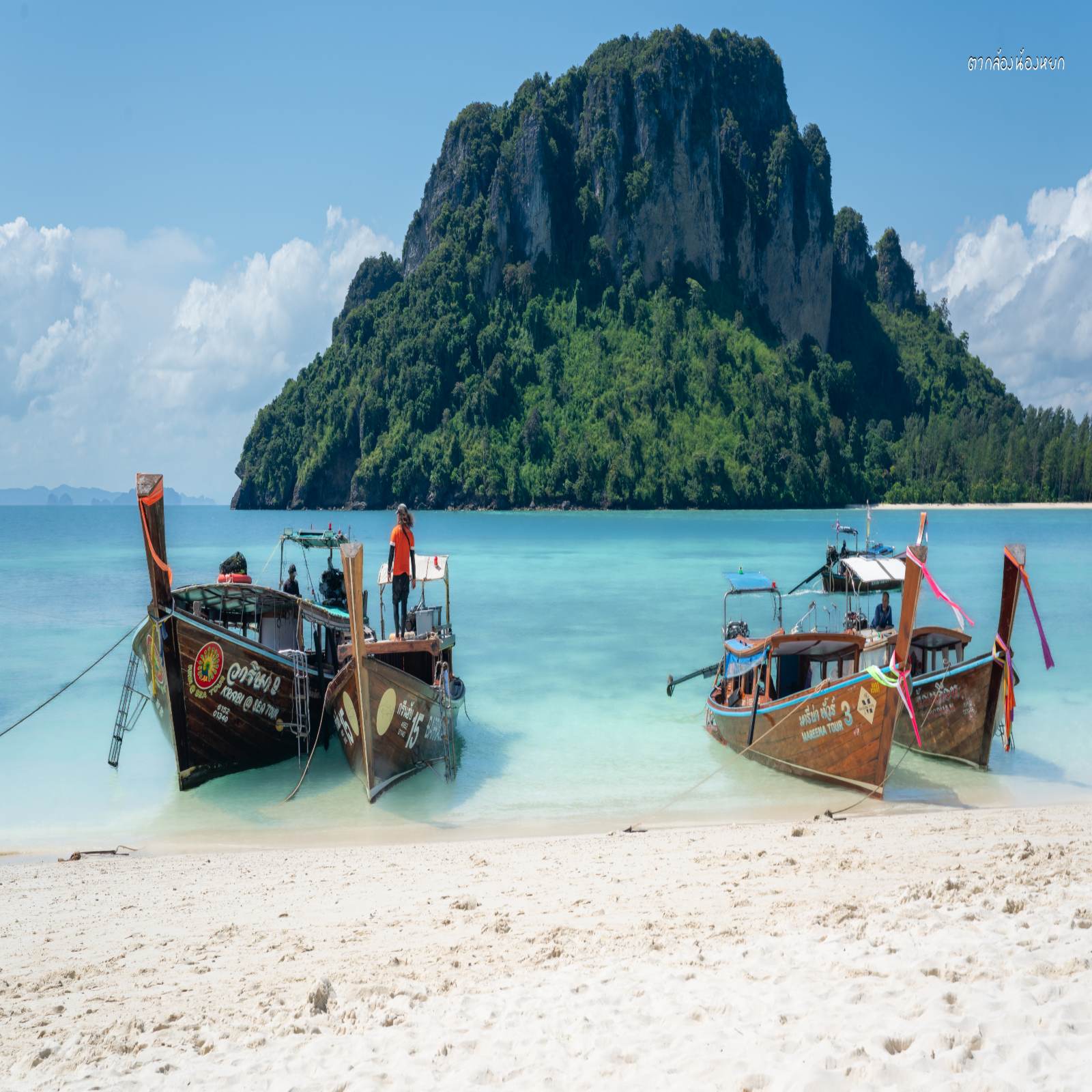 เรือดั้งเดิมจอดอยู่ริมทรายกับน้ำใส